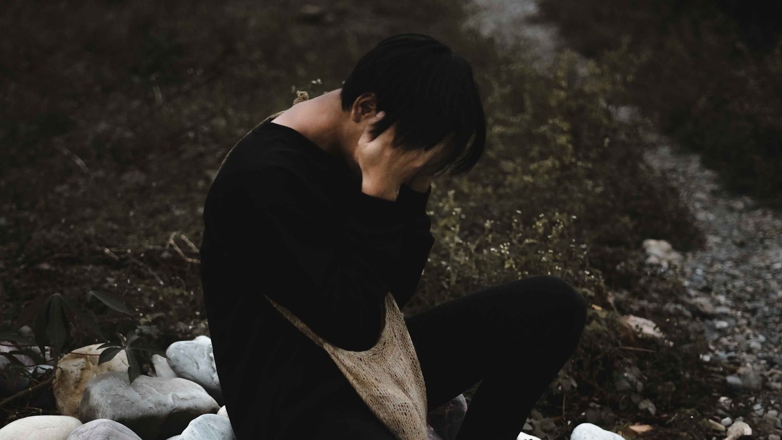 man in black shirt and gray pants sitting on ground: Trauma Counseling