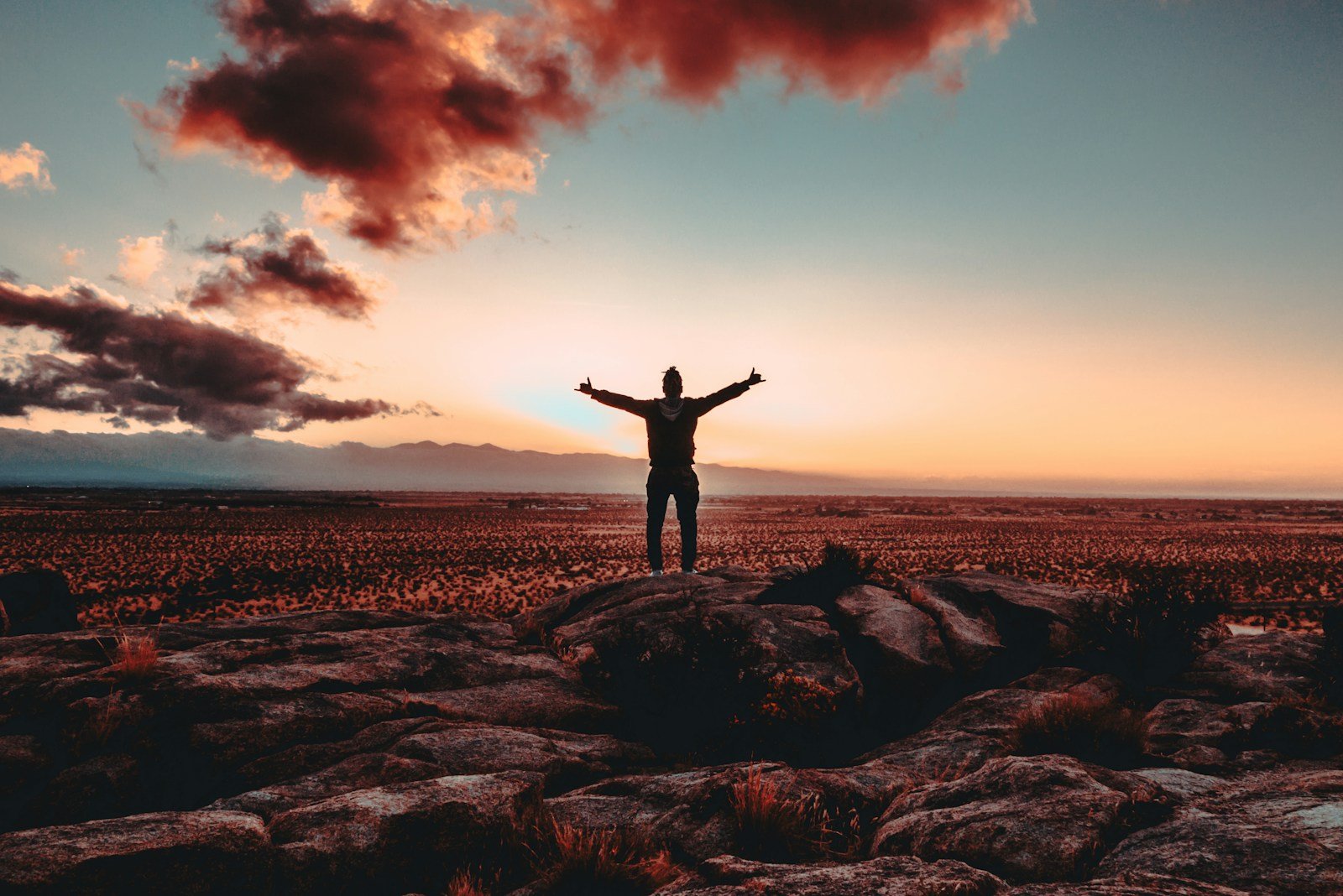 person standing on rock raising both hands showing Stress Unraveled