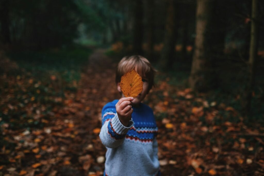 boy holding brown leaf covering his face : Navigating Hope: Developmental Disorders Counseling in Joliet